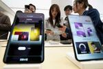 　店舗に展示されているファーウェイの新型スマートフォンを手に取る来店者＝３月２０日、北京（共同）