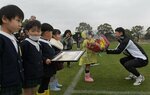 園児から花束を受け取る石井主将（右）＝宮崎県綾町の錦原サッカー場
