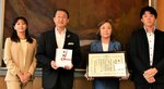 山本節共同代表（右から２人目）から目録を受け取った平井知事（同３人目）＝１１日、鳥取県庁