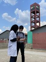 　ザンビアの病院前で話す清原さん（右）＝２０２１年１１月１８日（本人提供）