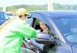 ドライバーに啓発グッズを手渡して安全運転をお願いする関係者（左）＝１２日、鳥取市円通寺の倉田パーキング
