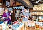 武将印を求める県外観光客と談笑する川越理事長（左）＝米子市灘町１丁目の米子まちなか観光案内所