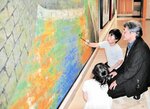 恐る恐る作品に筆を入れる子どもと、見守る山田さん＝豊岡市小島の県立円山川公苑美術館