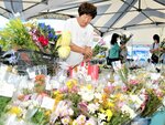  お盆の入りに備え、切り花をかごいっぱいに選ぶ買い物客＝１０日、鳥取市安長の愛菜館 