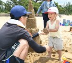 親子で砂遊びを楽しむ子ども（右）＝３１日、鳥取市浜坂の鳥取砂丘フィールドハウス