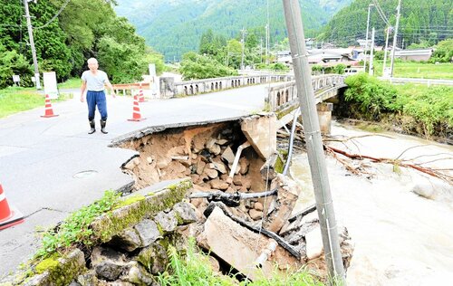 【路面崩壊】路面が崩れ、田んぼに水を送る土管などが壊れた穴鴨橋のたもとを指さす住民＝１６日午前１０時２０分、三朝町穴鴨の加谷川