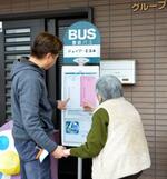 　豊鉄バスがグループホームに寄贈した「バス停」で、入居者（右）と「時刻表」を確認する施設長の武田誠さん＝２０２５年３月、愛知県豊橋市