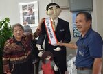  「石破かかし」に新しいたすきを掛けた八頭ふるさとかかし親の会の有志ら＝２日、鳥取市戎町の石破茂事務所 