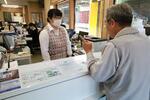 　「やまたけ」の営業所で従業員（左）とやりとりをする客＝２０２４年１月、茨城県かすみがうら市