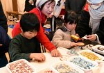 色とりどりのモザイクタイルを使ってコースターを作る子どもら