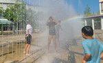 うだるような暑さの中、噴水で水浴びをする子どもたち＝２日、倉吉パークスクエア
