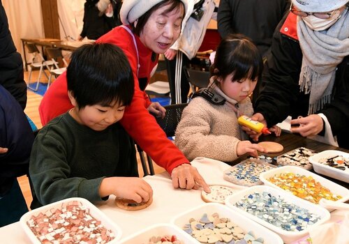 色とりどりのモザイクタイルを使ってコースターを作る子どもら