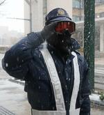 　雪の中ゴーグルを着用し、敬礼する青森県警の警察官＝６日、青森市