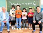 自分の名前が入った茶わんを手に、花井さん（右）らと笑顔を見せる子どもたち