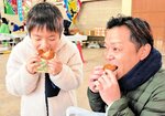 【舌鼓】
セコガニの身がたっぷりと入ったコロッケを頬張る親子。「サクサクしておいしい～」と大満足の様子＝浜坂漁港