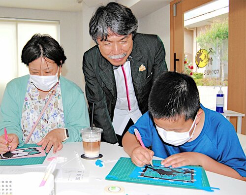 来館者の切り絵体験に助言する久保さん（中央）