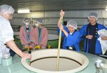 蒸し米やこうじが入ったおけを長い棒でかき混ぜる参加者＝６日、境港市大正町の千代むすび酒造
