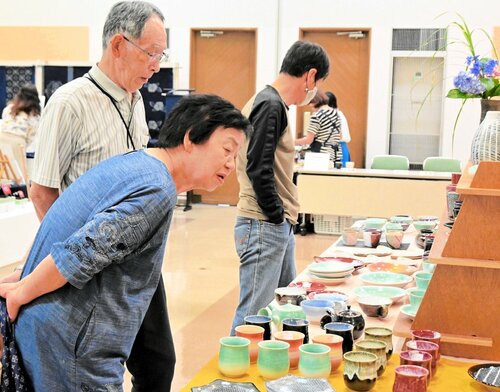 お気に入りの作品をじっくり探す来場者ら＝１１日、倉吉市上井町１丁目の日本海新聞中部本社ホール