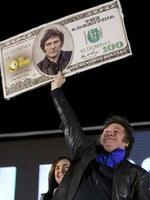 　自身の顔があしらわれた米ドル札のボードを掲げるミレイ氏＝１６日、アルゼンチン中部コルドバ（ＡＰ＝共同）