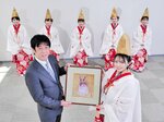 岡野総局長へ縁起物を手渡す福娘＝５日、大阪市北区の大阪日日新聞