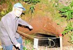 四王寺山に残る塹壕を指す谷口さん。鳥取県内でも地上戦が行われる可能性があったことを伝える貴重な戦争遺構だが、風化が進み、価値が失われつつある＝１日、倉吉市大谷