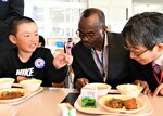 給食について説明を受けるカリクストさん（中央）＝１７日、岩美町新井の岩美南小
