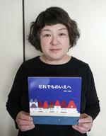 　絵本を手にする新井由木子さん＝２０２５年５月、埼玉県草加市
