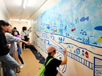 ＪＲ山陰線鎧駅の地下通路にイラストを描く参加者ら＝３日、香美町香住区鎧