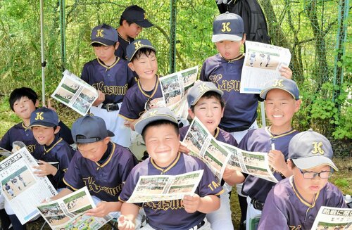 満面の笑みで特別号外に目を通す選手たち＝２８日、新温泉町湯の健康公園多目的グラウンド