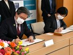 協定書に署名する高橋理事長（右）と野川会長＝７日、鳥取市本町３丁目の鳥取産業会館