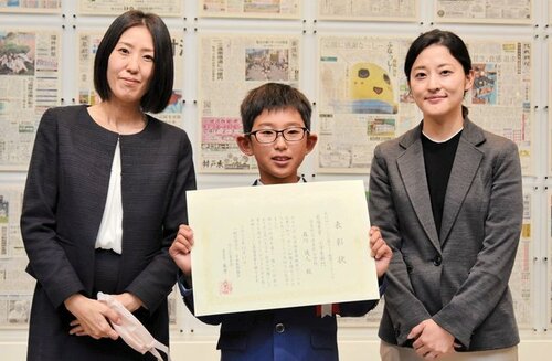 表彰を受けた森川君（中央）と母親の詩穂さん（左）、題材の記事を執筆した岩崎記者＝１７日、横浜市中区のニュースパーク