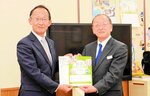 足羽教育長（左）に教材の冊子を手渡す入江理事長
