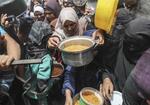 　４月３０日、ガザ地区北部ジャバリヤ難民キャンプで、食料を受け取るパレスチナ人ら（ゲッティ＝共同）
