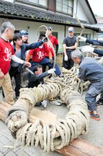 巨大な綱を編み上げていく住民や外国人留学生ら＝３日、三朝町三朝