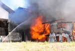 炎を上げている建物＝１３日午前８時５分、大山町長野