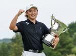　最終日、通算１５アンダーでツアー初優勝し、トロフィーを手にガッツポーズの金子駆大＝日野ＧＣ