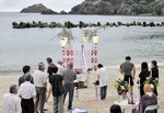浜辺に置かれた精霊船に読経とともに手を合わせる住民ら＝１５日夕、新温泉町諸寄