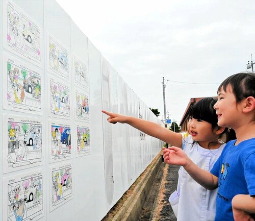 工事現場の囲いに展示されている園児の塗り絵作品