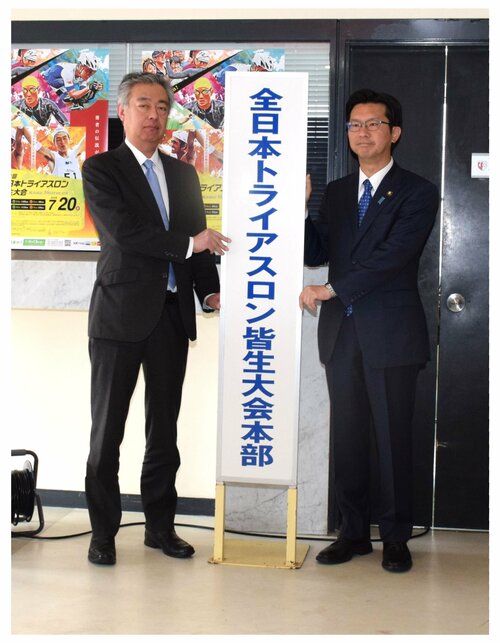 大会本部の看板を設置する伊木市長（右）と伊坂実行委員長＝２４日、米子市皆生温泉３丁目の皆生市民プール