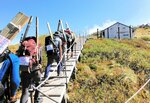 キャリーアップ運動で大山頂上木道まで桟木を運ぶボランティアら（鳥取県西部総合事務所提供）