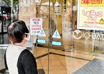 臨時休業を知らずに来店し、来年１月に閉店する店舗を不安げに見つめる買い物客＝１４日、松江市朝日町