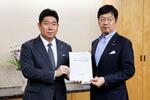 　阿達雅志総務副大臣（右）にインターネット上のヘイトスピーチ解消のための要望書を手渡す川崎市の福田紀彦市長＝２日午後、総務省