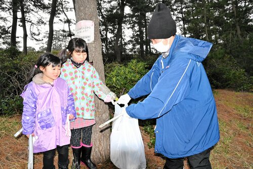 海潮音の森で捨てられたペットボトルを回収する家族連れ＝９日、鳥取市福部町湯山