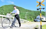 自転車を押しながら踏切を渡る生徒＝香美町香住区加鹿野の香住自動車教習所