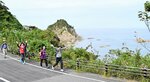 ダイナミックで美しい地形が続く城原海岸をバックにウオーキングを楽しむ参加者＝１４日、鳥取県岩美町田後