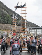 高さ約８メートルのはしごの上で技を披露する消防団員ら＝８日、鳥取市東町２丁目の擬宝珠橋