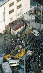 　オウム真理教の施設前に並べられたバリケードの車を挟んで待機する捜査員ら（手前）＝１９９５年３月２２日、山梨県上九一色村（当時）