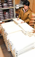 精米したコメを管理する田中社長。需要の高まりを受けて今年は増産に踏み切る＝４月２３日、鳥取県八頭町下坂