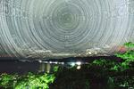 　石垣島天文台が撮影した地平線付近から上向きに延びる人工衛星の光跡。同心円状の光は星の動き＝２０２４年７月（国立天文台提供）