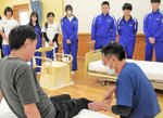 浜野さん（手前左）が吾郷さんのサポートでリハビリに取り組む様子を見学する生徒たち